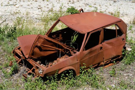 small rusty wrecked car at the roadside, somewhere in France