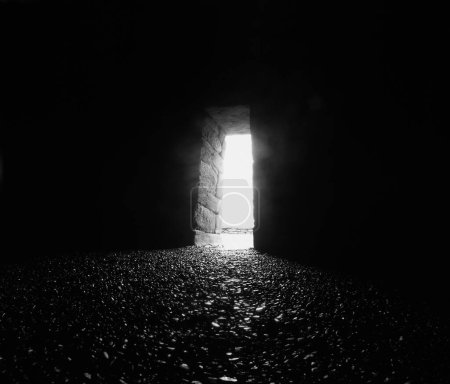 Eingang eines alten Steingebäudes, Clochan oder Bienenkorbhütte in Irland, helles Licht fällt auf einen mit Kieselsteinen bedeckten Fußboden