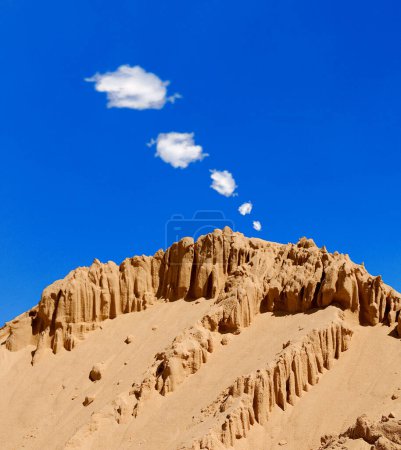 una montaña arenosa y rocosa, señales de humo en el cielo azul