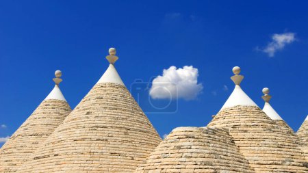 conical roof or cone roof of Trullo against blue sky and white fluffy cloud, near town of Alberobello, Apulia, Italy