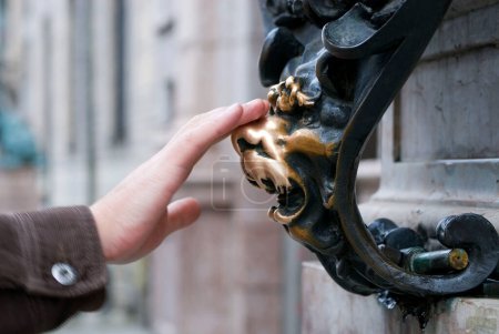 Lucky Lying Lion mit einer Hand, die sich die Nase reibt, am Odeonsplatz. Nasereiben bei den Löwen soll Glück bringen, München, Bayern, Deutschland