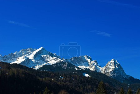 Schneebedeckte Wettersteinberge im Frühling, mit Alpspitze links, Zugspitze in der Mitte und Waxenstein rechts, von Klais, Bayern, Deutschland aus gesehen