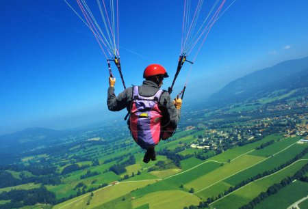 a man in a paraglider high above the meadows near Lenggries, pilot's perspective, Bavaria, Germany