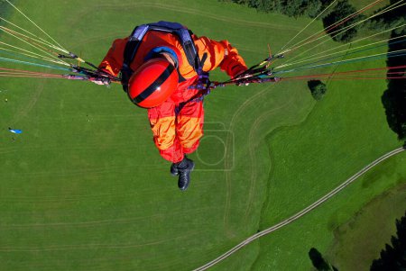 a man in signal red overalls in a paraglider high above the meadows near Lenggries, pilot's perspective, Bavaria, Germany, Europe