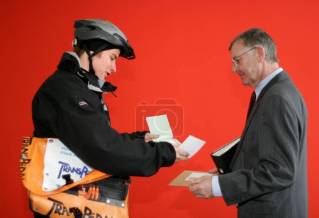 Foto de Múnich, Baviera, Alemania, 15 de febrero de 2005, un mensajero en bicicleta en invierno con bolsa de mensajería ha entregado un envío al cliente, un hombre de negocios, y pide una firma como confirmación de recepción - Imagen libre de derechos