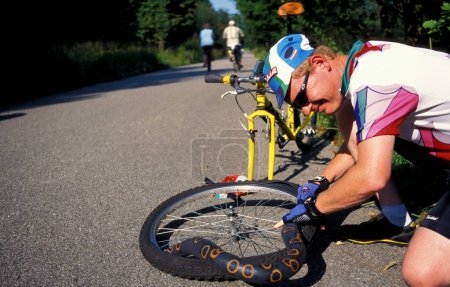 Foto de Munich, Baviera, Alemania; el 2 de julio de 2007, desafortunado ciclista en la carretera arregla su neumático de bicicleta por enésima vez - Imagen libre de derechos