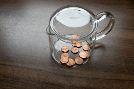 A glass container, money box, with some one cent, dollar cents, US currency, symbol for poverty