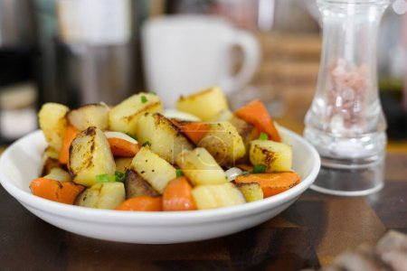 Roasted potatoes with carrot, onion, herbs and spices. Potato wedges with herbs.
