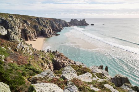 Porthcurno, Cornwall, Royaume-Uni - Vue sur la plage Pedn Vounder avec Logan Rock et l'océan par une journée ensoleillée