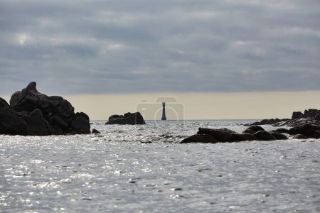 Isles of Scilly, Großbritannien - Bishop Rock Leuchtturm in der Ferne zwischen Felsen im Vordergrund.