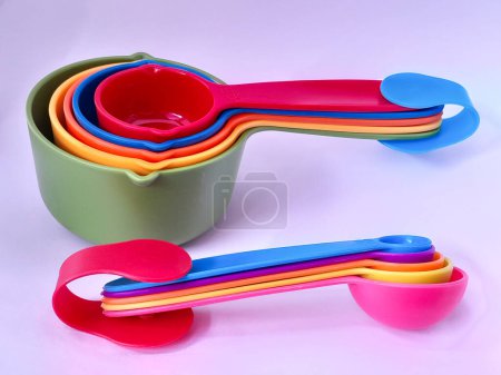 Téléchargez les photos : Tasses et cuillères à mesurer colorées imbriquées utilisées dans la cuisson et la cuisson isolées sur fond blanc. - en image libre de droit
