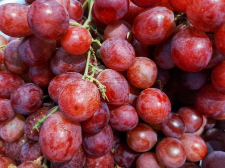 Close up of bunch ripe red grapes display on supermarket shelf.