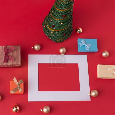 Creative concept of Christmas decorations, tree and gifts. Minimal layout on red background wtih copy space.