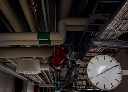 a closeup shot of a fire alarm system around all other industrial pipes leading a corridor