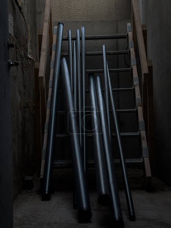 Metal pipes laying on wooden stairs, ready to be picked up to install into the building, blue collar workers building fire security sprinkler systems