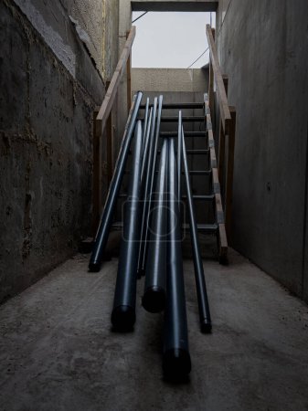 Metal pipes laying on wooden stairs, ready to be picked up to install into the building, blue collar workers building fire security sprinkler systems