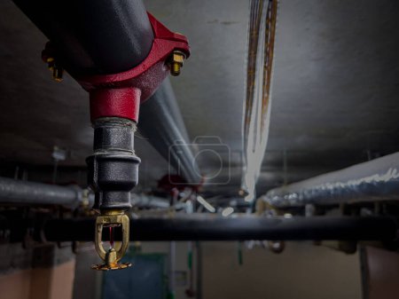 a closeup shot of a fire security sprinkler system installation in a house, red parts on gray pipes