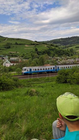  Train in a green mountain valley. Photo.Train in a small mountain village, boy, green slopes.