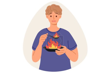 Man eats very spicy food, causing burning sensation in mouth due to overabundance of pepper, holding plate and spoon with flame. Guy eats spicy dish with spices, makes dissatisfied grimace