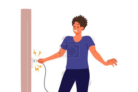 Man receives electric shock when inserts plug into socket and feels pain due to breakdown of electrical equipment. Electric shock for guy in casual clothes holding wire with wet hands
