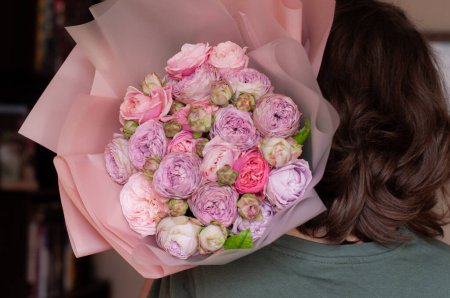 the girl holds a bouquet of tender roses on her shoulder