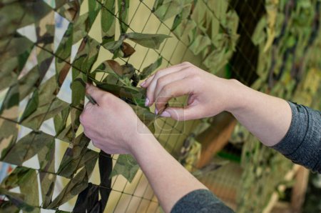 un voluntario crea una red de camuflaje para los militares con sus manos, la guerra en Ucrania