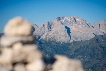 Closeup view of Peak Marmolada with glacier during summer clouless morning with blurry rocks in foreground