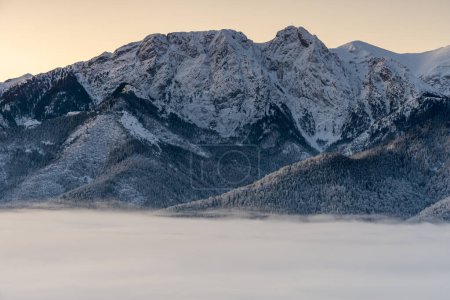 Giewont mountain, Poland Tatra Mountains in the morning with fog in the valley. Cloudless sky with sunrise colors. View from Gubalowka Mountain in Zakopane Town and Koscielisko Village.