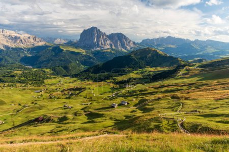 Vista desde la montaña Seceda en Val Gardena en los Dolomitas italianos en el soleado día de verano con hierba verde en primer plano y cielo azul con nubes.