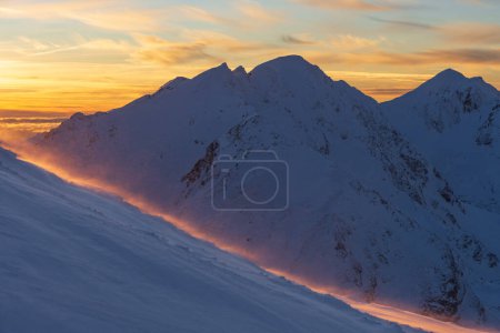 Paysage panoramique de montagne d'hiver au coucher du soleil, Tatras Ouest. Vue de Volovec aux Rohace. Ciel coloré et illuminé par le soleil neige soufflée par le vent