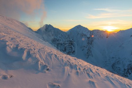 Coucher de soleil d'hiver coloré dans les montagnes Tatras Ouest. Vue de Volovec aux Rohace. Ciel coloré et illuminé par la neige du soleil au premier plan.