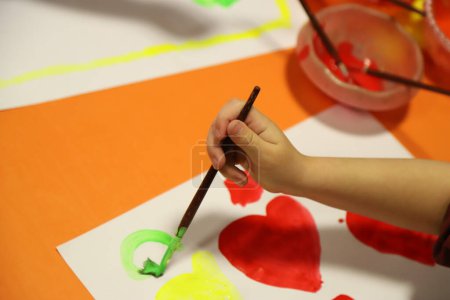 Preschool children painted drawings with temperas and brushes. Kids in kindergarten drawing. Children in art class in the school classroom.
