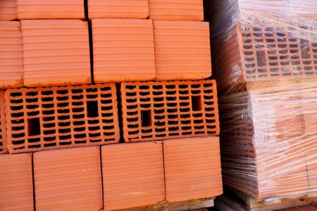 Ceramic bricks on pallets. Palletized construction material. Bricks for construction of houses and buildings. Concept of construction, building, works of architecture, urban planning. Red brick.