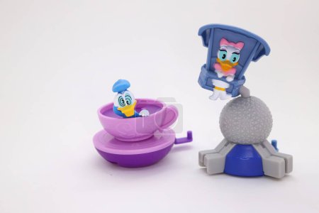 Photo for Dizzy Donald Duck in rotating cup and Daisy Duck in a flying game at Disney's park. Cartoons characters in amusement park. Collectible toys for children on white isolated background. - Royalty Free Image