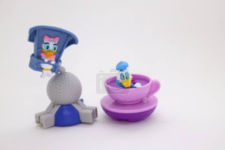Photo for Daisy Duck in a flying game and dizzy Donald Duck in rotating cup at Disney's park. Cartoons characters in amusement park. Collectible toys for children on white isolated background - Royalty Free Image