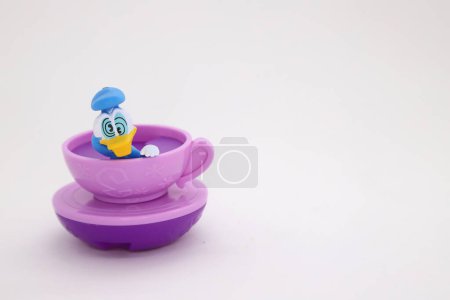 Téléchargez les photos : Dizzy Donald Canard en tasse rotative au parc d'attractions Walt Disney. Jouet en plastique pour enfants avec personnage Disney sur fond blanc isolé. Chiffre amusant pour les enfants. - en image libre de droit