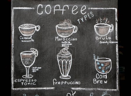 Tafel in Kreide geschrieben mit verschiedenen Kaffeesorten. Handgeschriebene und gemusterte schwarze Tafel. Bar Restaurant Plakat. Karamell Macciato, Marokko, Brule, Espresso, Frapuccino, Kaltes Gebräu.