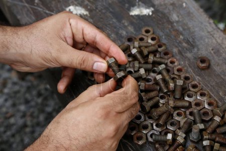 Photo for Hands of a mechanic or worker. Man working with rusty nuts and bolts. Manual work table. Oil dirty hands. Employee. Worker. Close up. Nut and bolt insert. - Royalty Free Image