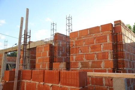 House under construction with red ceramic bricks. Building under construction with exposed beams and structures. Concept of bricklayer work, masonry, house construction, architecture, building. Buil.