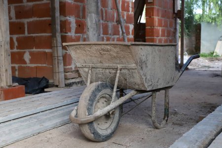 Photo for Wheelbarrow at home construction site. Loading tool for bricklayers and builders. Conceptual image of construction and masonry. - Royalty Free Image