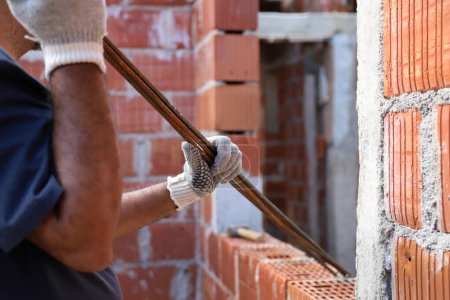 Photo for Mason carrying an iron. Builder working on construction site. Professional bricklayer working on house construction. Concept of architecture, construction, industry, construction worker, work, man - Royalty Free Image