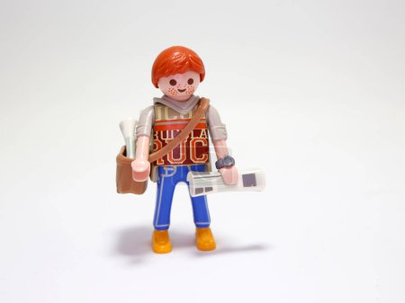 Photo for Playmobil doll. Newsboy. New's paper seller. Young boy. Paperboy. Newspaper. Redhead with freckles. Boy. Employee. Happy person. Isolated white. Toy. - Royalty Free Image