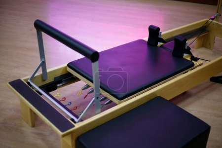 Réformateur et boîte pilates civière. Équipement pour les cours de Pilates. Lit pilates en bois et cuir avec tendeurs colorés.