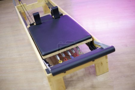 Reformer and box pilates stretcher. Equipment for Pilates classes. Wooden and leather pilates bed with colorful tensioners.