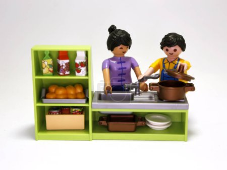 Foto de Playmobil dolls. Couple cooking. Man and woman making dinner. Family in their kitchen. Food preparation. Multicultural couple. Toys for children. Isolated white. - Imagen libre de derechos