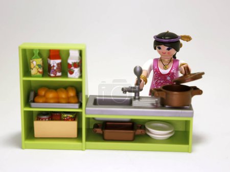 Foto de Playmobil dolls. Woman cooking. Girl making dinner in their kitchen. Food preparation. Toys for children. Isolated white. Plastic figures. - Imagen libre de derechos