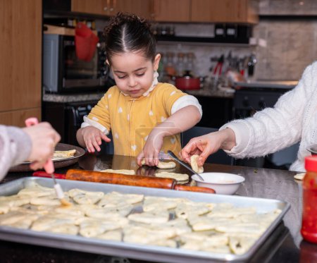 Enkelin hilft Großmutter bei der Herstellung von Gebäck in Küche, Mutter liebt Emotionen