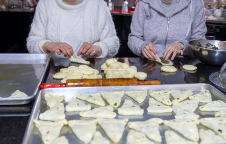 preparing arabic traditional pastries by female hands stuffing them with spinach and red chili