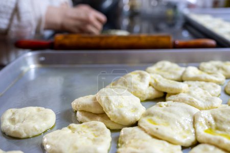 old woman hands using rolling pin to flatten the dough  on black marble  covered with oil