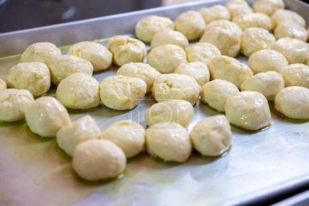 Dough balls on metal tray with olive oil to make sure it is not sticking and can be shaped later to be used and stuffed